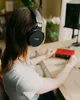 A person wearing headphones sits at a desk with audio equipment. Anteprima dell’immagine prodotto