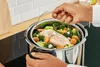 A person is using a steamer insert to cook salmon and vegetables in a pressure cooker. Náhľad obrázku produktu