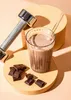 A chocolate protein shake with chocolate pieces and a dumbbell. Produktbild-Vorschau