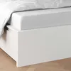 A close-up view of a white bed frame with a white fitted sheet and a white duvet cover. Produktbild-Vorschau