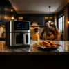 A family is in the background of a kitchen scene, with an air fryer and food in the foreground. Náhľad obrázku produktu
