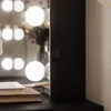 A close-up view of a vanity mirror with lights and books on the surface. Produktbild-Vorschau