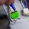 A close-up view of a green Shelly DALI Dimmer Gen3 device being installed with wires connected. Produktbild-Vorschau