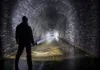 A person holding a flashlight in a dark, wet tunnel. Podgląd zdjęcia produktu