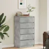 A chest of drawers with a concrete gray finish is placed in a room next to a large plant and a sofa. Náhled obrázku produktu