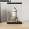 A white and gold rocket figurine displayed inside a clear acrylic case on a wooden surface. Produktbild-Vorschau