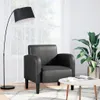 A black armchair is shown in a well-lit room with a floor lamp and a plant. Anteprima dell’immagine prodotto
