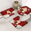 A Christmas-themed toilet seat cover and matching bath mats are displayed on a bathroom floor. Náhľad obrázku produktu