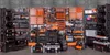 A large collection of toolboxes and organizers are displayed against a textured gray wall. Anteprima dell’immagine prodotto