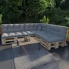 An outdoor seating area with a sectional sofa made of pallets and cushions, a coffee table, and a rug. Voir les images du produit