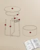 An exploded view of a round side table with labeled parts, alongside an open instruction manual. Produktbild-Vorschau