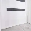 Close-up view of a white door with a dark gray insert and a white baseboard, resting on a tiled floor. Anteprima dell’immagine prodotto