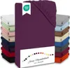 A stack of folded jersey fitted sheets in various colors, with a prominent aubergine colored sheet in the foreground, featuring an OEKO-TEX logo and a color swatch with text. Produktbild-Vorschau