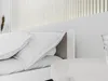 A close-up view of a bed with white pillows and a white headboard. Náhled obrázku produktu