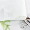 A close-up view of a white sheer curtain with a floral pattern, showing the hem and a portion of the fabric. Produktbild-Vorschau