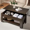 A dark brown lift-top coffee table with storage, shown in a living room setting with a couch in the background. Produktbild-Vorschau