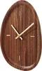 A close-up studio shot of a wooden wall clock with a unique, organic shape and gold hands. Voir les images du produit