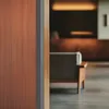 A view into a lobby or reception area, with a focus on a wooden panel and a blurred background showing furniture and lighting. Produktbild-Vorschau