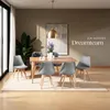 A dining room setting with a wooden table and four gray chairs, a large plant, and a painting on the wall. Náhled obrázku produktu