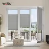 A modern living room with a view of a balcony through a large window with blinds. Produktbild-Vorschau