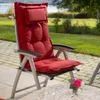 A red chair cushion on a patio chair, with a garden and a body of water in the background. Produktbild-Vorschau