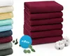 A stack of folded burgundy towels next to a stack of towels in various colors. Produktbild-Vorschau