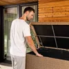 A man is opening a large storage box outdoors. Produktbild-Vorschau