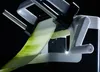 A close-up shot of a vegetable slicer with a long, thin slice of cucumber being processed. Produktbild-Vorschau