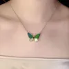 Goldkette mit Schmetterlingsanhänger mit grünen und türkisfarbenen Flügeln und Strass-Akzenten, auf der Brust einer Person getragen Náhľad obrázku produktu