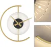 A modern wall clock with a gold frame and a white face with radiating light effects. Produktbild-Vorschau