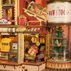 A detailed close-up of a ROKR 3D wooden puzzle, depicting a whimsical "Dream Gift Factory" scene with various components like a conveyor belt, gift boxes, and a Christmas tree inside a glass cylinder. Podgląd zdjęcia produktu