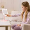 A young girl is touching a pink cat-shaped makeup mirror with a light-up frame. Voir les images du produit