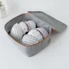 A grey fabric organizer box filled with bras, with the lid open. Voir les images du produit