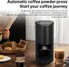 A coffee powder press is shown on a table next to a glass of coffee, bread, and cookies. Produktbild-Vorschau