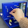 A hand is placing a white peg into a Battleship game board. Náhľad obrázku produktu