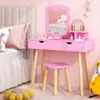 A pink vanity table and stool set for children, placed in a bedroom setting with pink walls and a bed. Produktbild-Vorschau