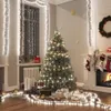 A festive Christmas scene with a decorated tree, fireplace, stockings, and gifts, illuminated by string lights. Voir les images du produit
