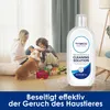 A mother and child playing with a dog and toys in a living room, with a bottle of cleaning solution prominently displayed. Produktbild-Vorschau
