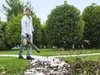 A man is using a leaf blower in a garden. Produktbild-Vorschau