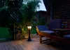 A garden patio at dusk with a solar-powered lantern and outdoor furniture. Produktbild-Vorschau