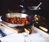 A still life arrangement of ingredients and cookware, featuring a pan of cherry tomatoes. Anteprima dell’immagine prodotto