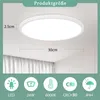 A white round LED ceiling light is shown mounted on a white ceiling, with curtains visible in the background. Below the light, there are icons and text indicating product features. Anteprima dell’immagine prodotto