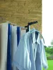 A light blue shirt hanging on a drying rack with other items in the background, outdoors. Voir les images du produit