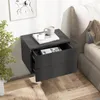 A gray floating nightstand with two drawers is shown next to a bed. One drawer is slightly open, revealing a book inside. A cup and a phone are on top of the nightstand. A plant is in the foreground. Anteprima dell’immagine prodotto