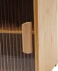 A close-up view of a wooden cabinet with a wooden handle and clear, ribbed doors. Náhled obrázku produktu