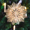 A straw star ornament hanging on a Christmas tree with decorative candles. Produktbild-Vorschau