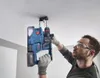A man is using a cordless hammer drill to drill into a ceiling. Voir les images du produit
