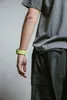 A close-up shot of a person's arm wearing a bright green smartwatch band and a gray t-shirt. Anteprima dell’immagine prodotto