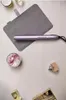 A flat lay of a hair straightener and accessories on a light-colored surface. Voir les images du produit