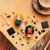 Two LEGO BrickHeadz figures, one resembling Merida from Brave and the other resembling Moana, are arranged on a wooden table with scattered LEGO bricks and accessories. Produktbild-Vorschau